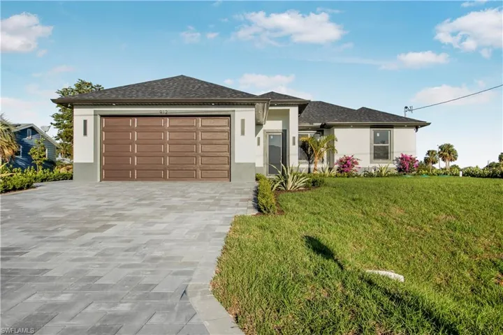 Prairie-style home with stucco siding, decorative driveway, a shingled roof, an attached garage, and a front yard