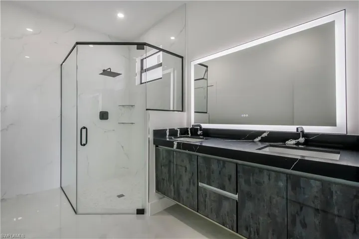 Full bathroom with double vanity, a marble finish shower, and a sink