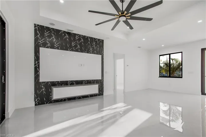 Empty room featuring a tray ceiling, recessed lighting, a ceiling fan, and visible vents