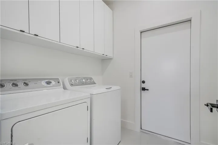 Washroom featuring cabinet space and washing machine and dryer