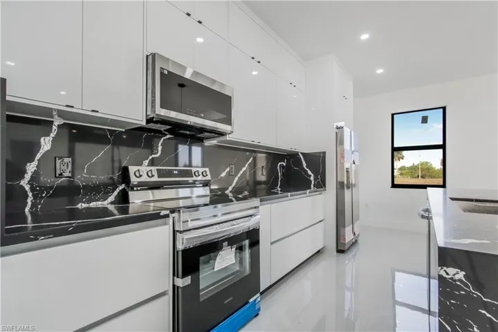 Kitchen with recessed lighting, stainless steel appliances, white cabinets, modern cabinets, and tasteful backsplash