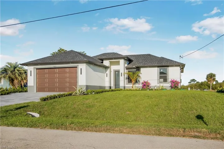 Prairie-style house with a garage, concrete driveway, a front yard, and stucco siding