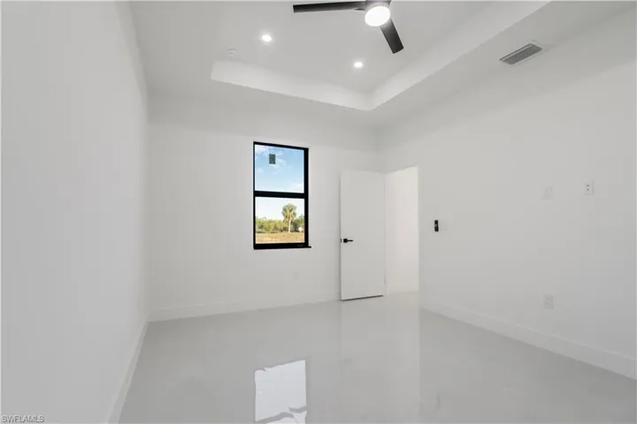 Unfurnished room with a ceiling fan, a raised ceiling, baseboards, and visible vents