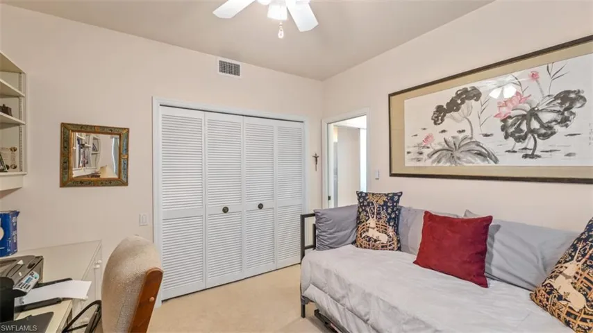 Guest Bedroom (2) featuring a closet, light colored carpet, ceiling fan, and an office area