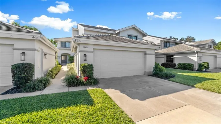 View of front facade featuring stucco siding, a front lawn, concrete driveway, and a tiled roof