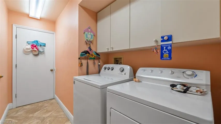 Laundry room featuring cabinet space, washing machine and dryer, and light tile patterned flooring