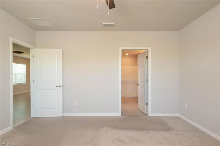 Unfurnished bedroom with carpet, tile patterned floors, and ceiling fan