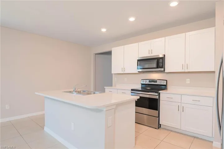 Kitchen featuring appliances with stainless steel finishes, light tile patterned floors, light countertops, white cabinets, and recessed lighting