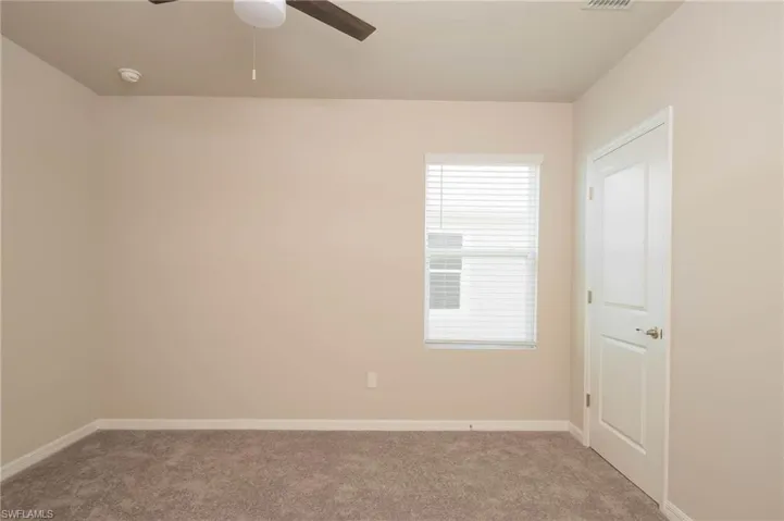 Carpeted spare room featuring baseboards and ceiling fan