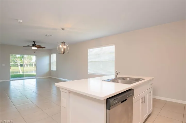 Kitchen with light tile patterned flooring, dishwasher, plenty of natural light, and hanging light fixtures