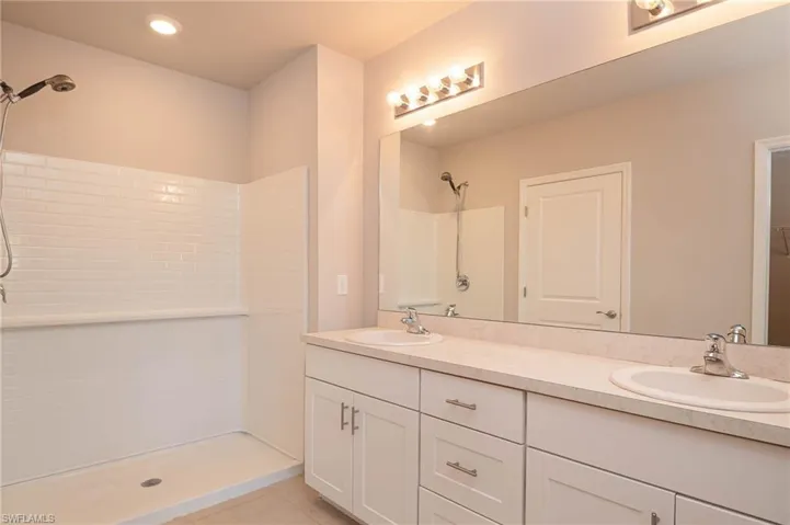 Bathroom with tiled shower, double vanity, tile patterned flooring, and recessed lighting
