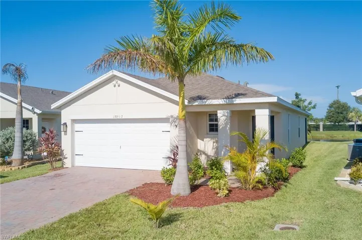Ranch-style home featuring stucco siding, roof with shingles, a front lawn, and decorative driveway