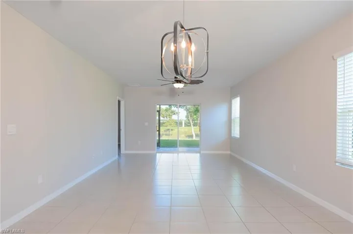 Spare room featuring light tile patterned floors, a chandelier, and a ceiling fan