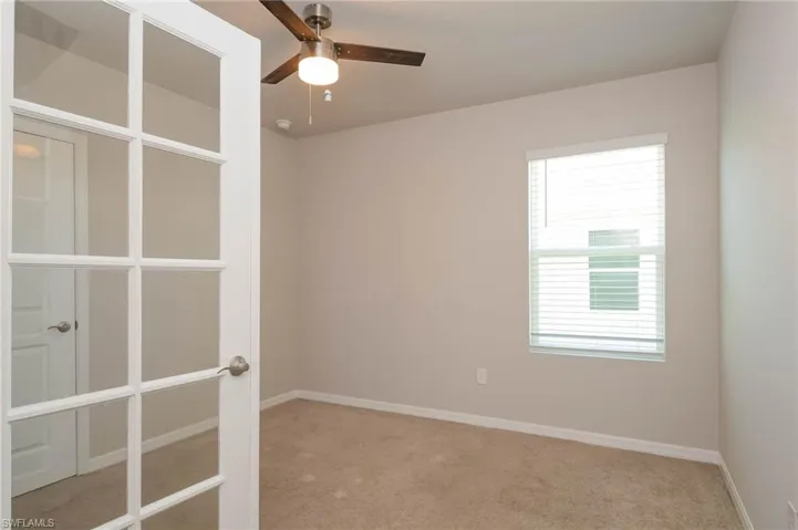 Carpeted spare room with baseboards and a ceiling fan