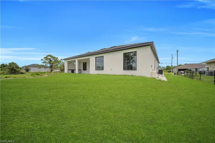 Expansive grassy lawn with a covered patio area and large windows