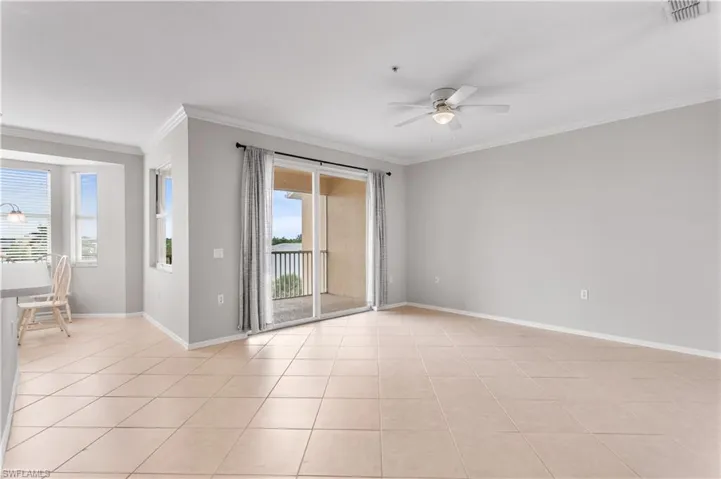 Tiled empty room featuring ceiling fan and crown molding