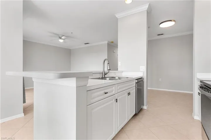 Kitchen featuring white cabinetry, crown molding, light tile flooring, and ceiling fan