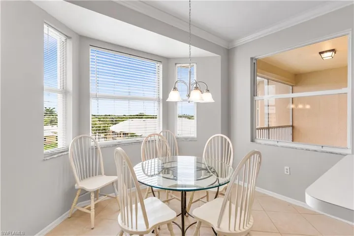 Dining space with a chandelier, a wealth of natural light, ornamental molding, and light tile floors