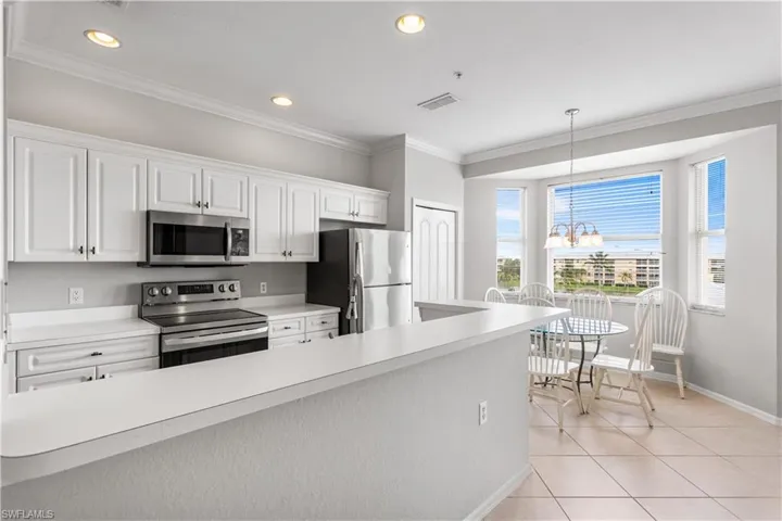 Kitchen with white cabinetry, appliances with stainless steel finishes, decorative light fixtures, a chandelier, and light tile floors
