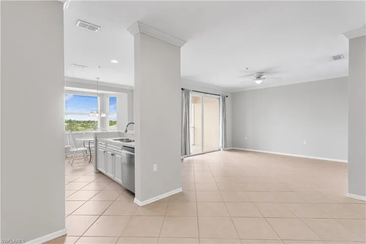 Tiled empty room with ceiling fan, crown molding, and sink