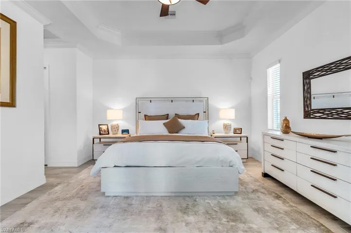 Bedroom with ceiling fan, a raised ceiling, and crown molding