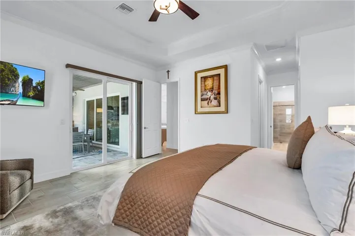 Bedroom featuring access to exterior, connected bathroom, ornamental molding, ceiling fan, and light wood-type flooring