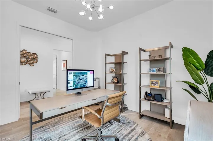 Office with light hardwood / wood-style floors and an inviting chandelier