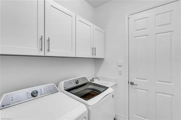 Clothes washing area with cabinets, sink, and independent washer and dryer