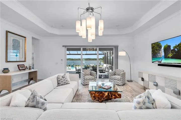 Living room featuring a tray ceiling, crown molding, and a chandelier