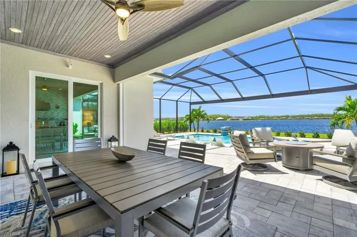 View of patio with a lanai, ceiling fan, and a water view