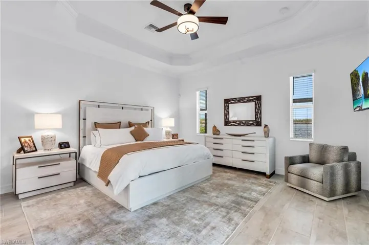 Bedroom with ornamental molding, a raised ceiling, and ceiling fan