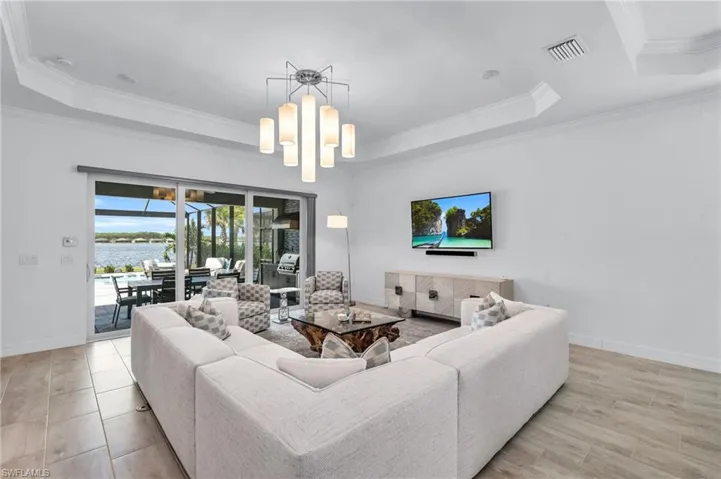 Living room with crown molding, a chandelier, and a tray ceiling