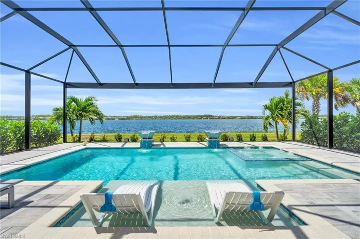 View of pool featuring glass enclosure, a patio, and a water view