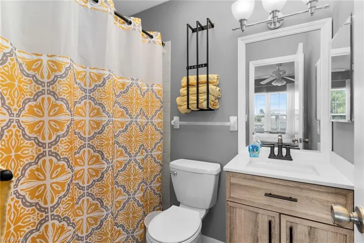 Bathroom with a shower with curtain, vanity, and a ceiling fan
