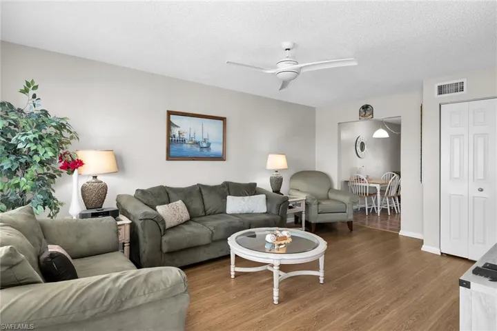 Living room featuring a textured ceiling, wood finished floors, and a ceiling fan