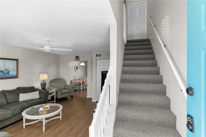 Stairway featuring a textured ceiling, wood finished floors, and a ceiling fan