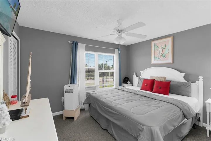 Bedroom with dark colored carpet, a textured ceiling, and ceiling fan