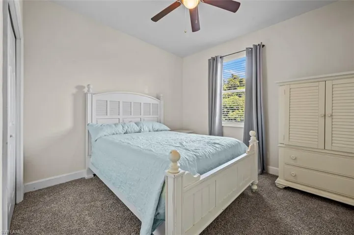 Carpeted bedroom featuring a closet and ceiling fan