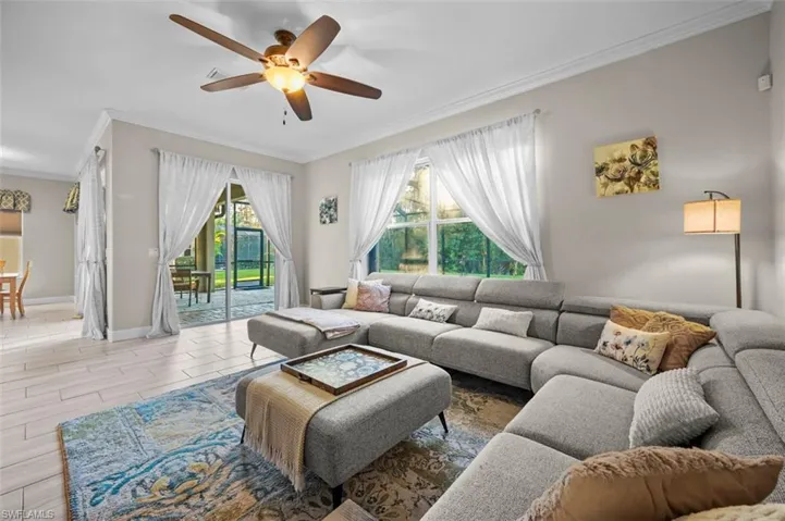 Living room with light hardwood / wood-style floors, plenty of natural light, crown molding, and ceiling fan