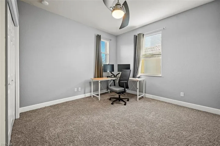 Carpeted office space featuring ceiling fan
