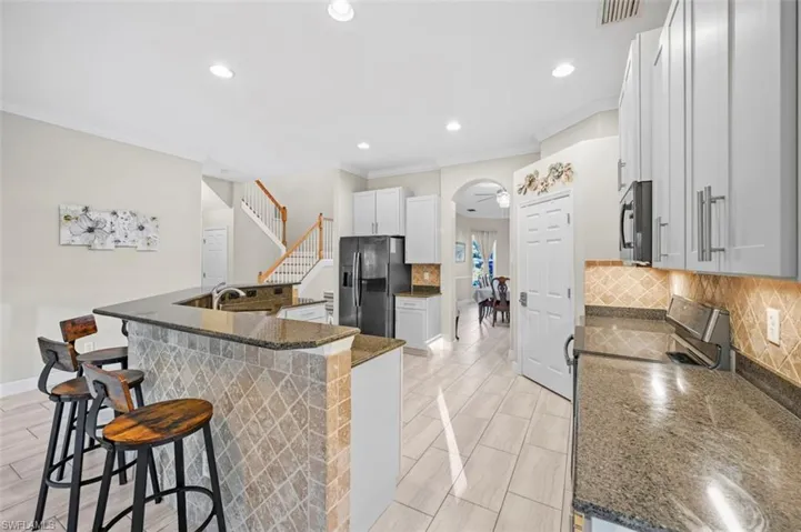 Kitchen featuring dark stone counters, crown molding, a kitchen bar, white cabinetry, and stainless steel appliances