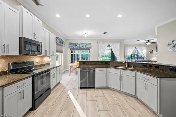 Kitchen featuring dark stone countertops, white cabinetry, sink, and stainless steel appliances