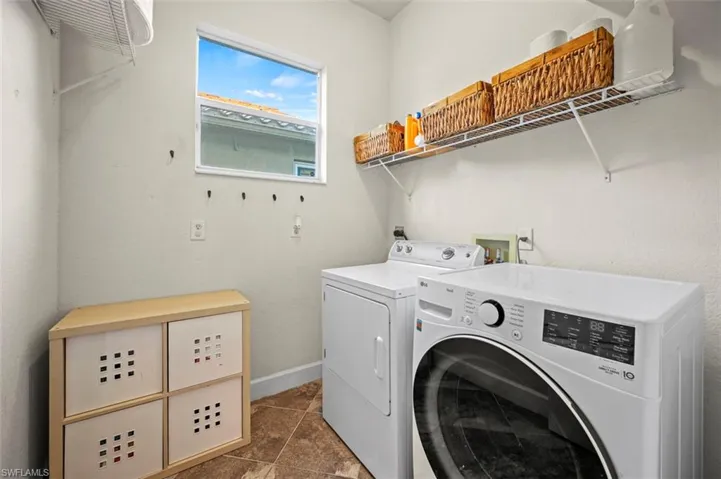 Clothes washing area featuring dark tile patterned floors and independent washer and dryer
