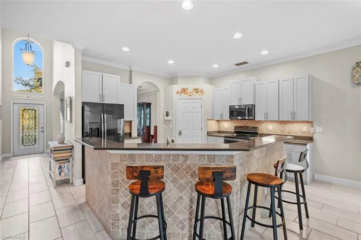 Kitchen with white cabinets, a kitchen island, a kitchen bar, and stainless steel appliances