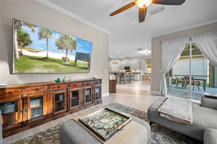 Living room with ceiling fan, light wood-type flooring, and ornamental molding