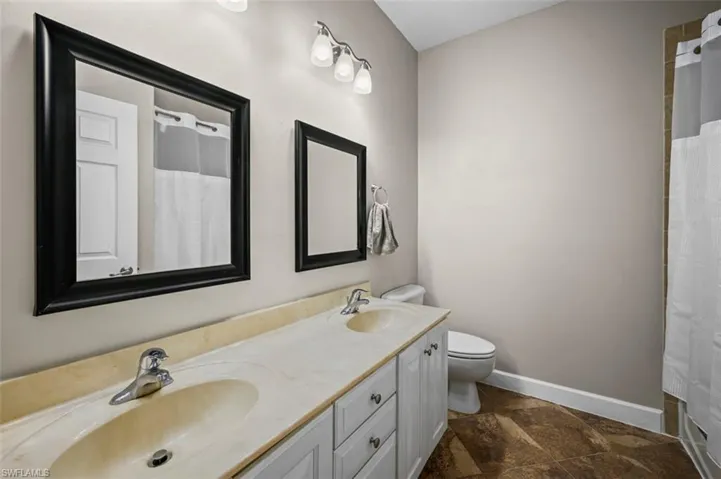 Bathroom with a shower with curtain, tile patterned flooring, vanity, and toilet