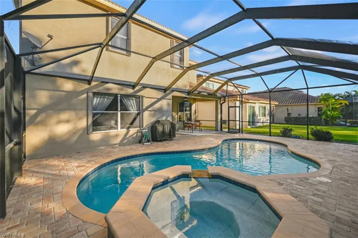 View of swimming pool with an in ground hot tub, a patio, and a lanai