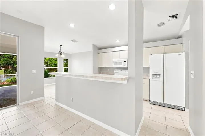 Open-concept kitchen and living area featuring a breakfast bar, white cabinetry, and a suite of white appliances