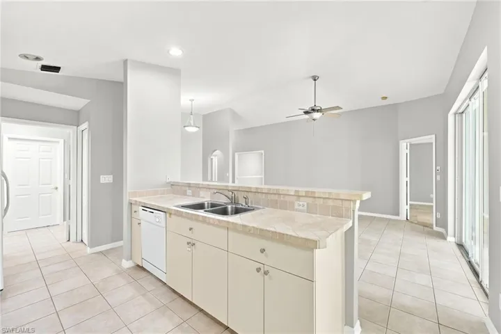 Open-concept kitchen with a breakfast bar, dual stainless steel sinks, and tile flooring
