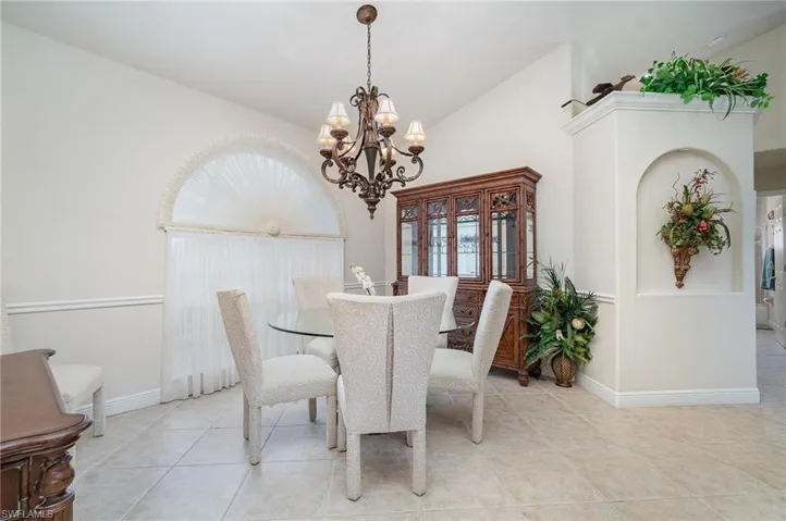 Dining space featuring high vaulted ceiling, light tile patterned floors, a notable chandelier, and baseboards